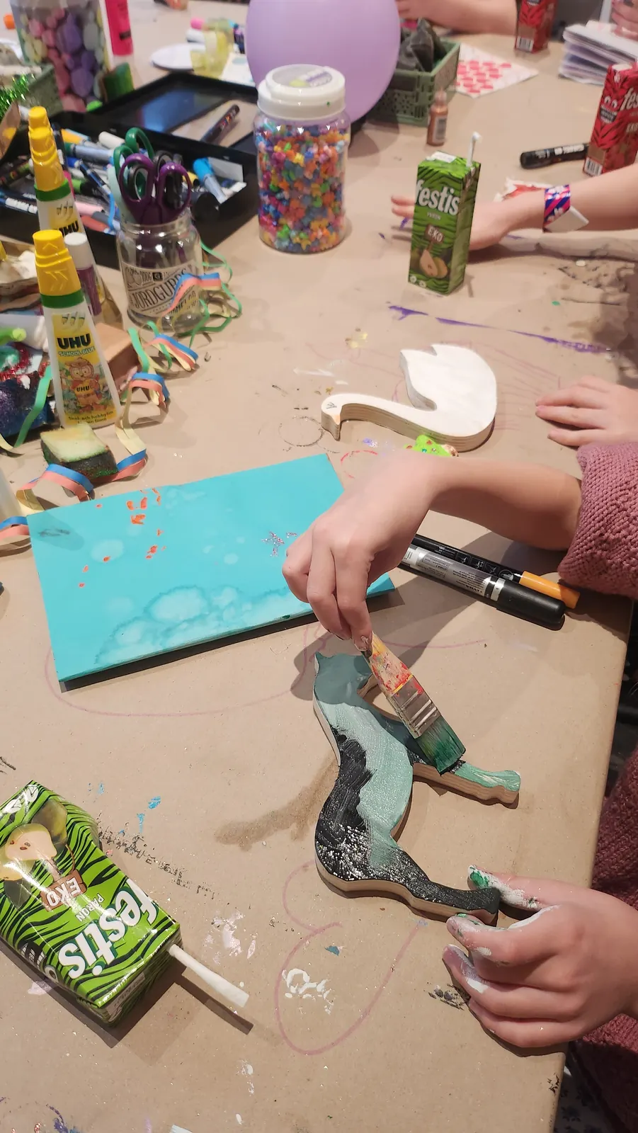 Målning av träfigurer vid pysselbordet – en kreativ aktivitet för barnkalas i Kungälv.