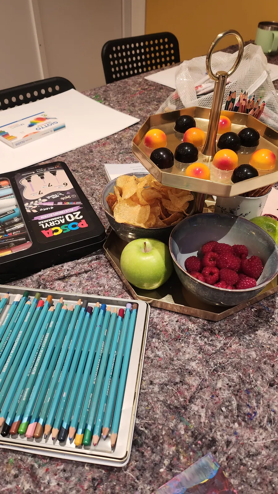 Färgpennor, målarpennor, frukt och snacks på ett förberett pysselbord.