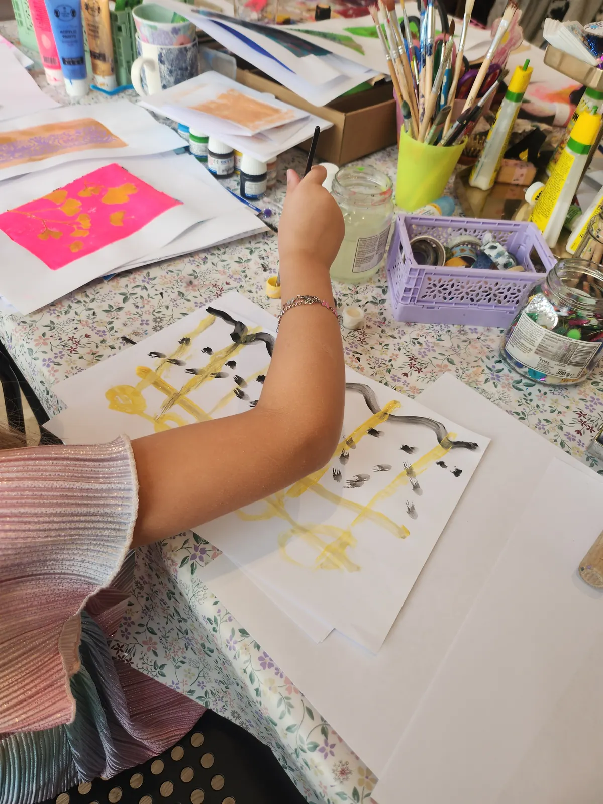 A child painting on paper with a brush at a colourful craft table in Kungälv.