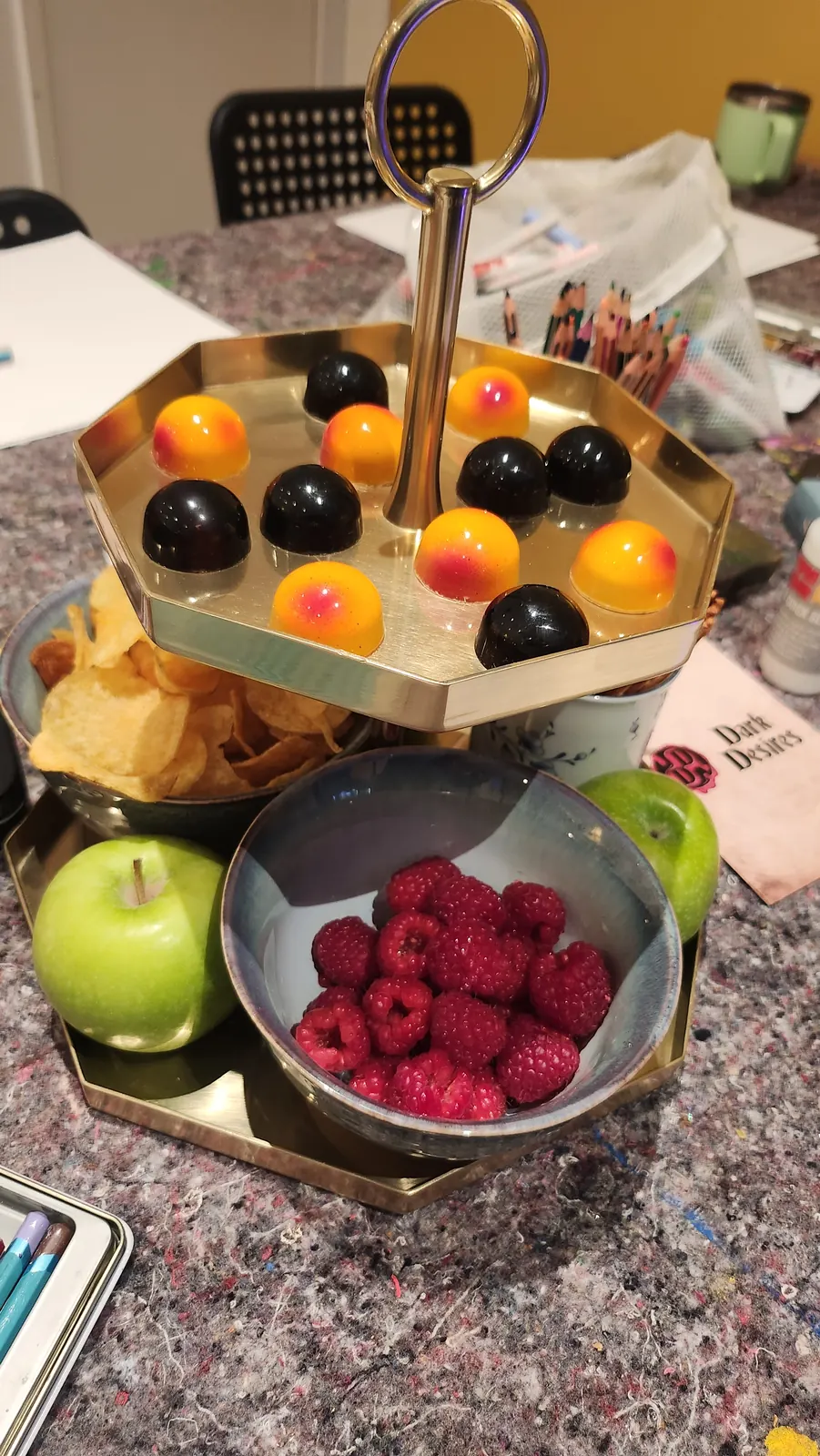 Ett serveringsfat med frukt, hallon, chips och små färgglada godsaker på pysselbordet.