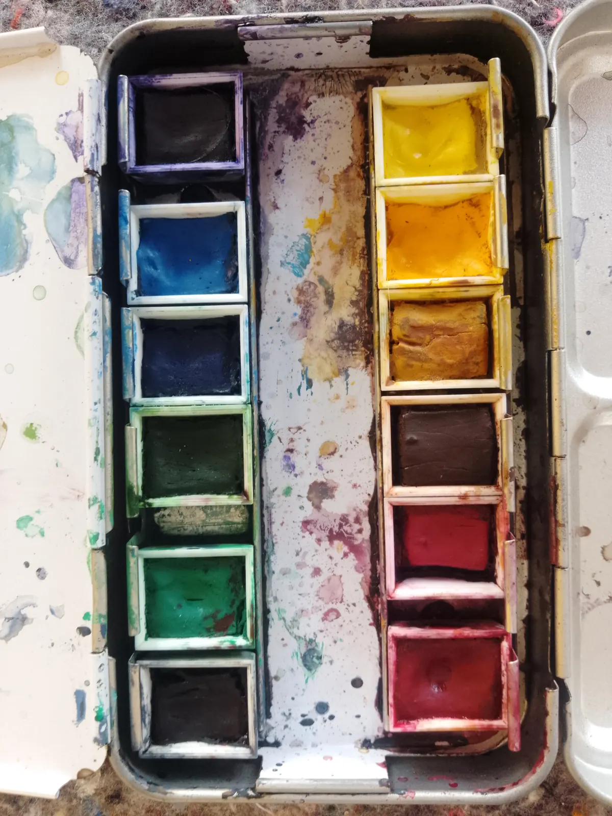 Watercolour paints in a well-used palette for painting and creative work.